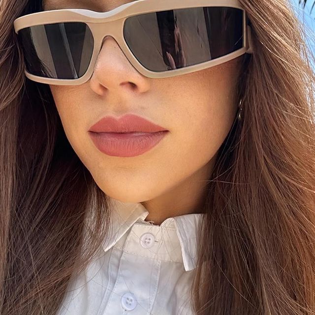 A close up of a woman wearing sunglasses and a white shirt