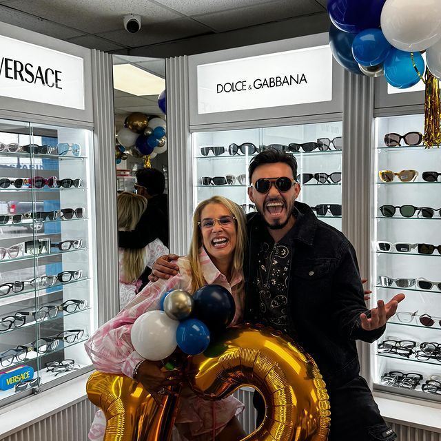 A man and a woman are posing with balloons in front of a store that says versace