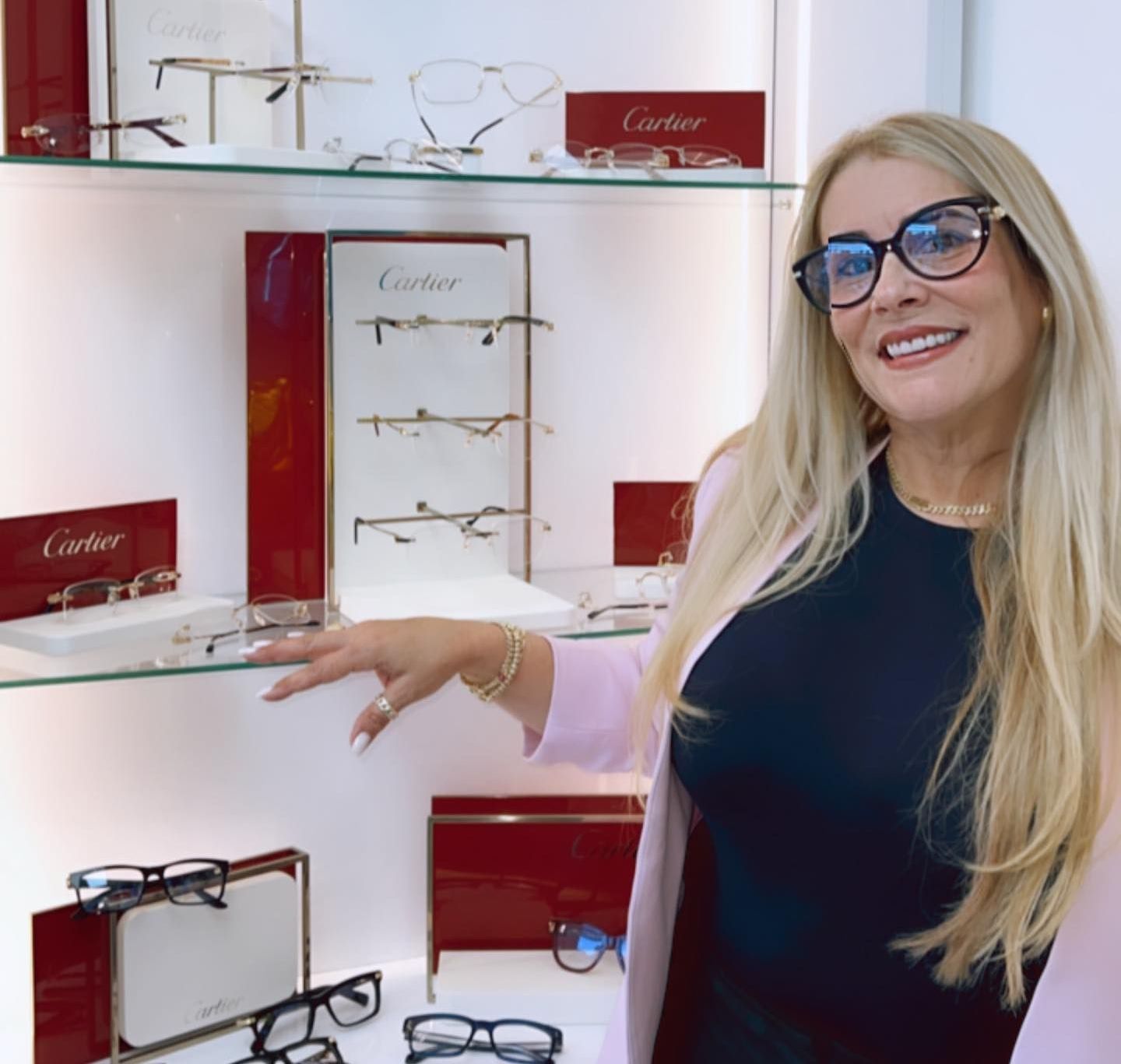 A woman wearing glasses stands in front of a display of cartier glasses