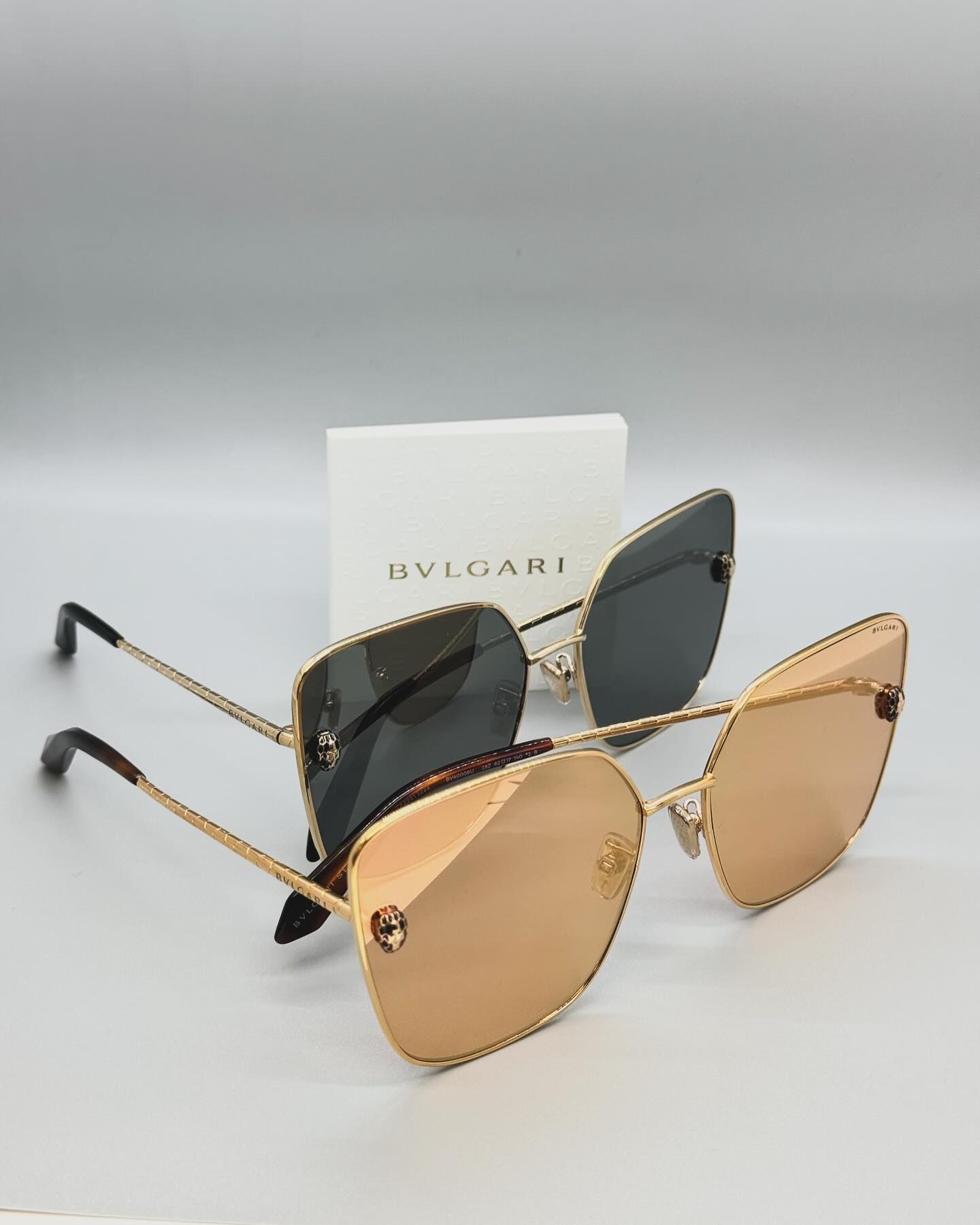 A pair of bvlgari sunglasses are sitting on top of each other on a table.