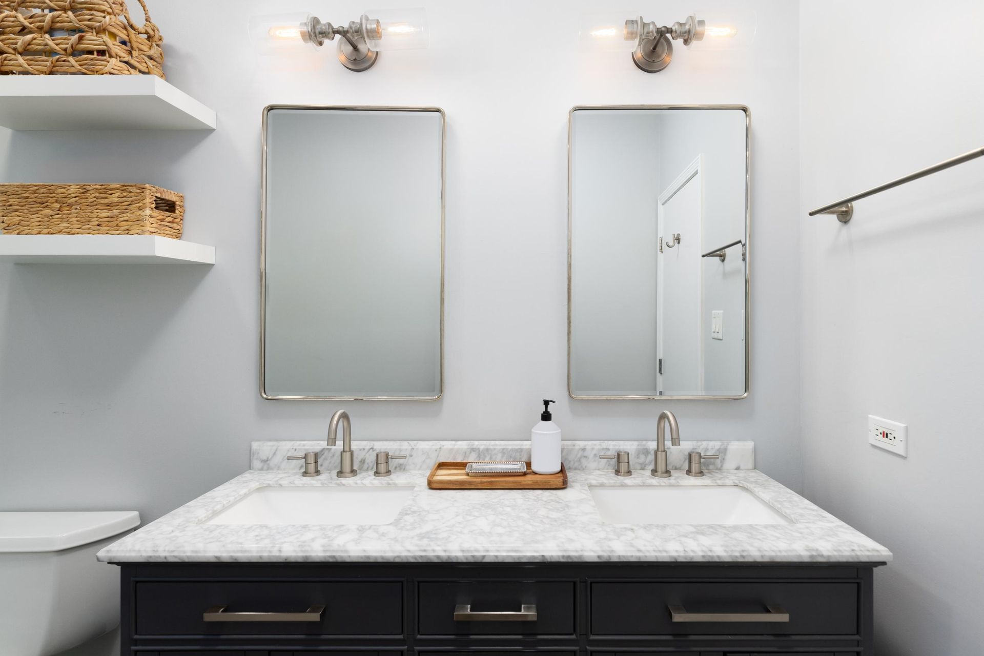 Modern bathroom vanity with two mirrors, dark cabinets, and white marble countertop
