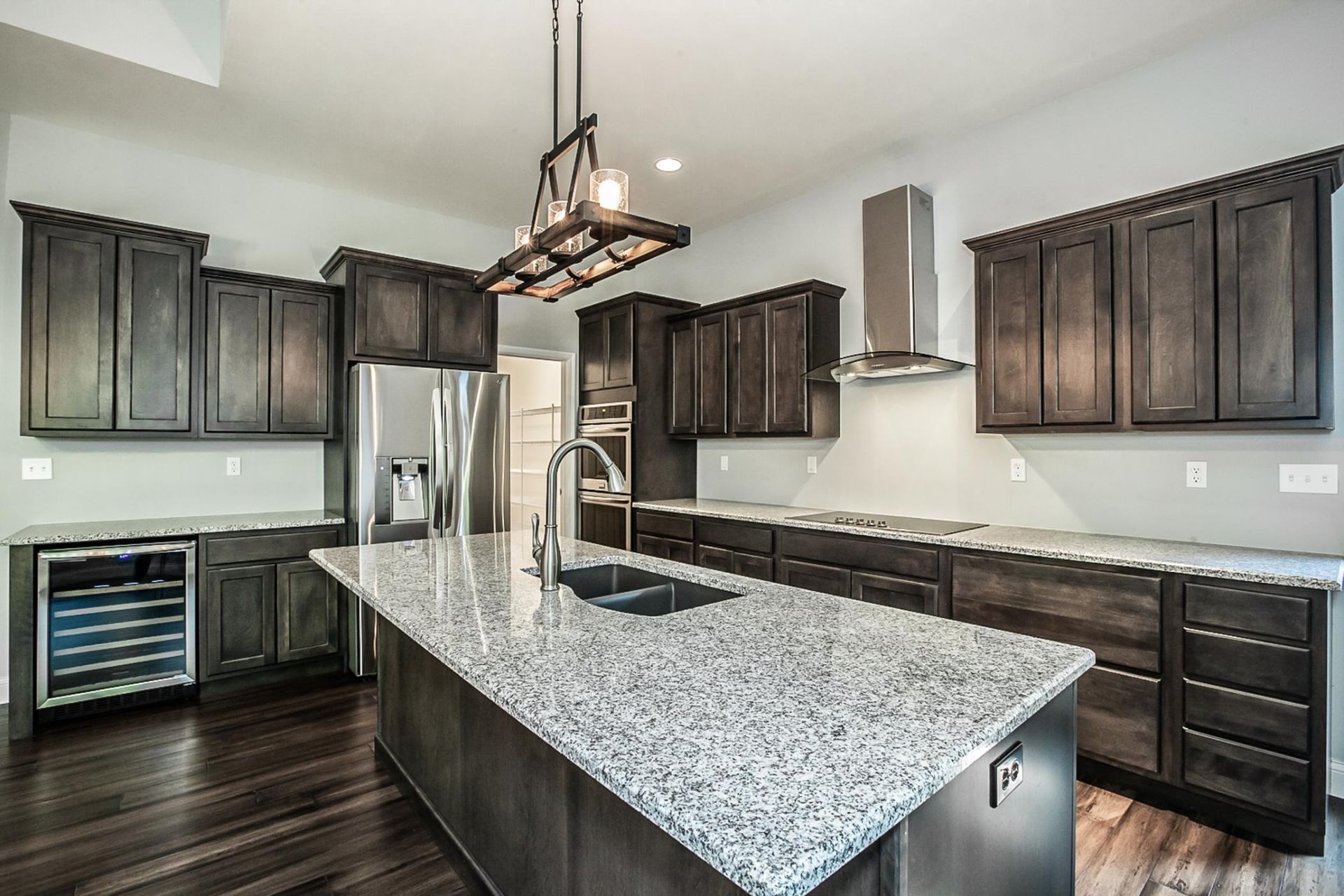Modern kitchen with dark cabinets, granite island, stainless appliances, and pendant light fixture