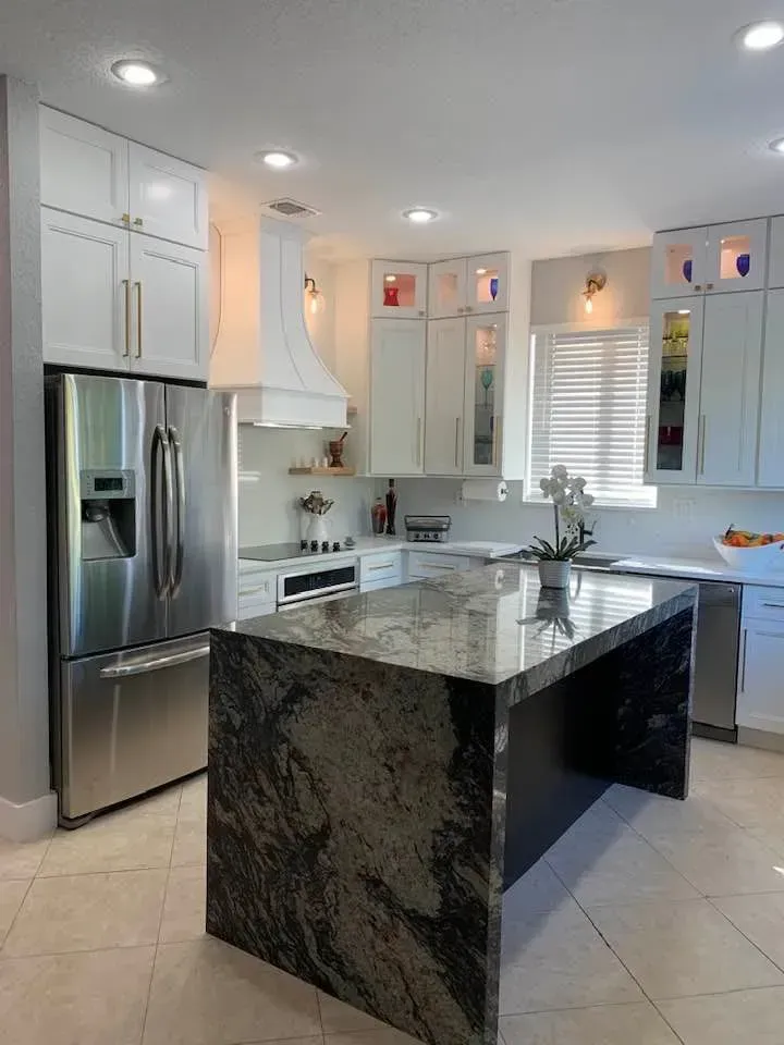 Bright modern kitchen with stainless steel appliances and a dark marble island under recessed lights
