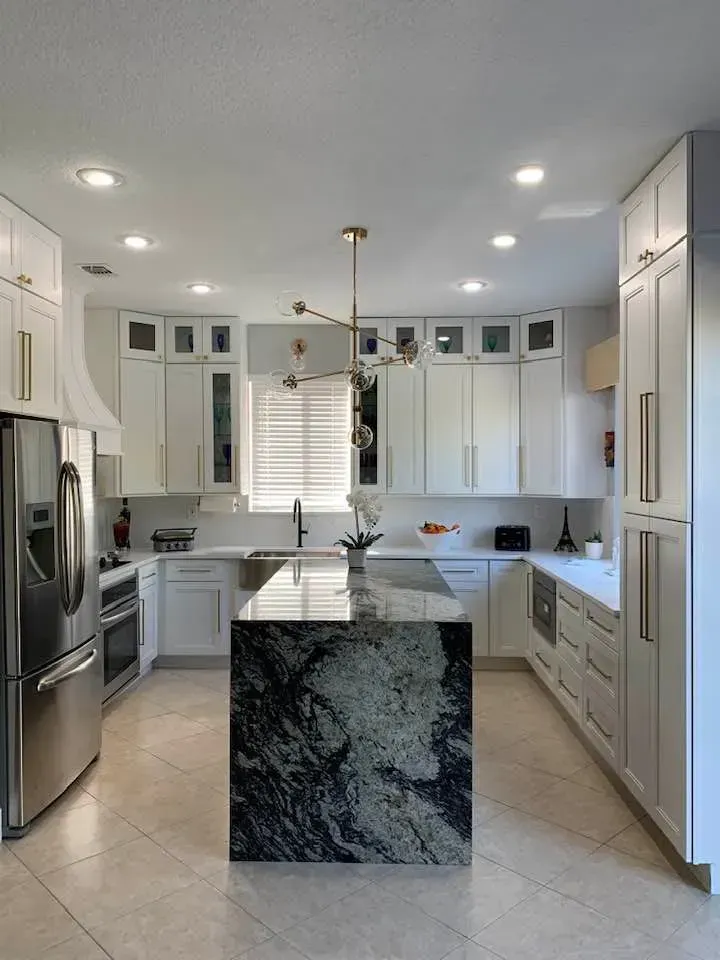 Modern white kitchen with island, stainless appliances, and dark granite countertop