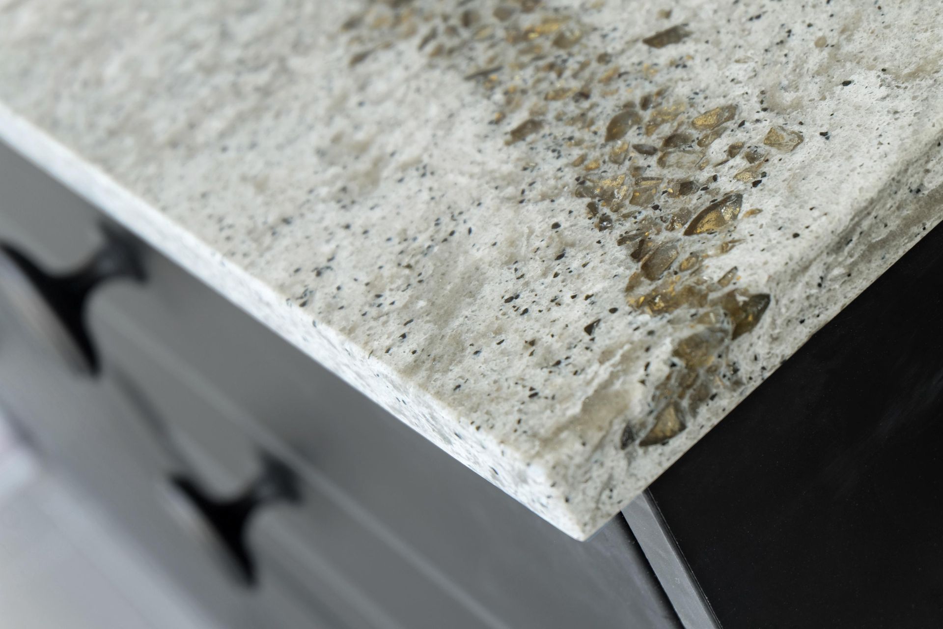 Close-up of a dirty, speckled white countertop corner with stains and grime.