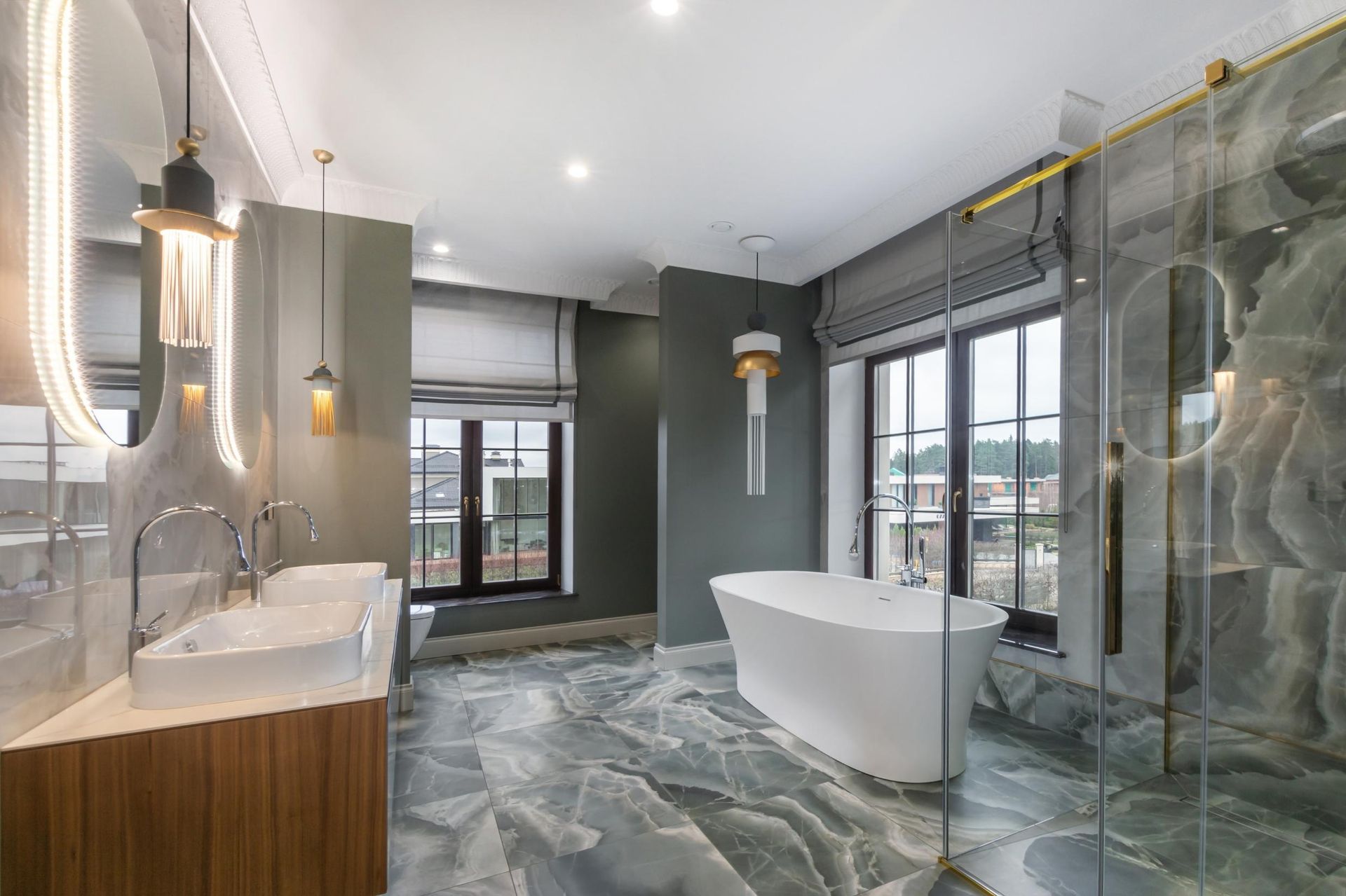 Modern gray bathroom with freestanding tub, glass shower, double vanity, and large windows