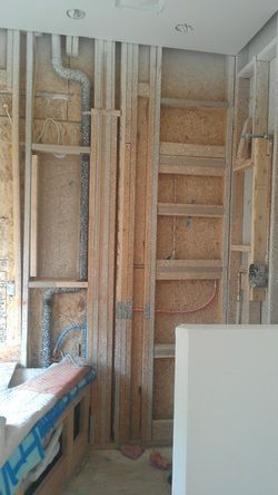 A bathroom under construction with wooden beams and pipes.