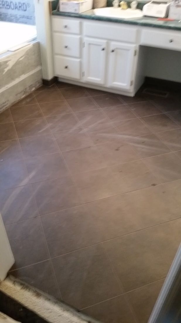 A bathroom with a wooden floor and white cabinets.