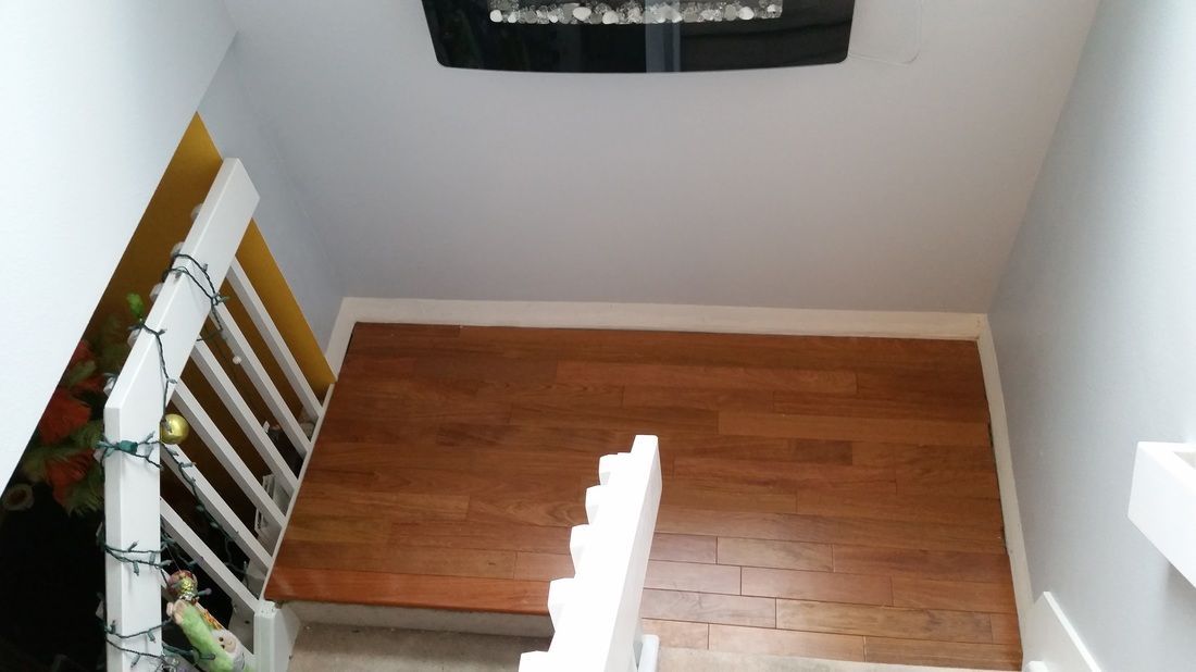 A staircase with a wooden floor and a white railing