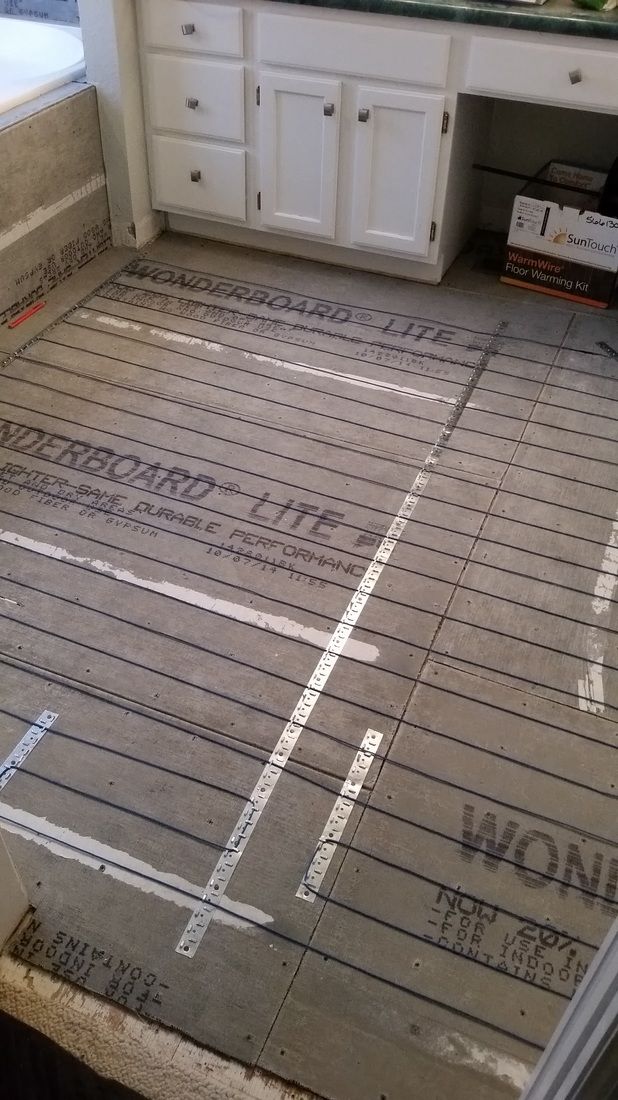 A bathroom with a heating system being installed on the floor.