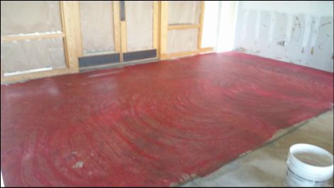 A room with a red floor and a white bucket on the floor