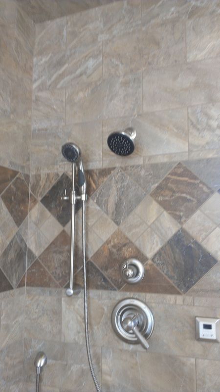 A shower head is sitting on top of a tiled wall.