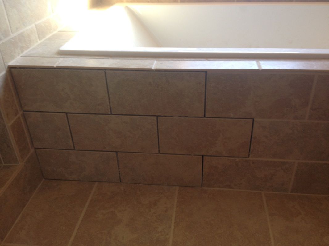 A bathtub in a bathroom with a brick wall surrounding it