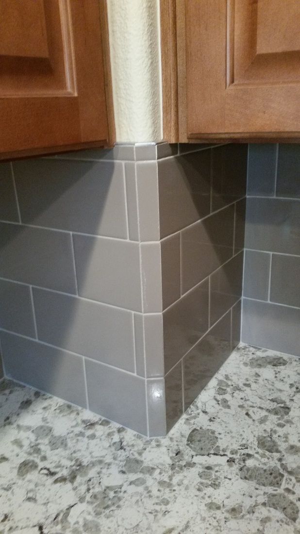 A kitchen corner with gray tiles and a granite counter top.