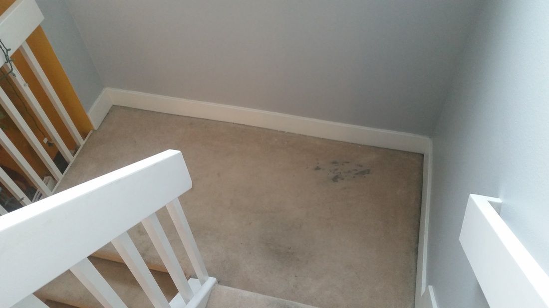 A staircase with a white railing and a dirty carpet
