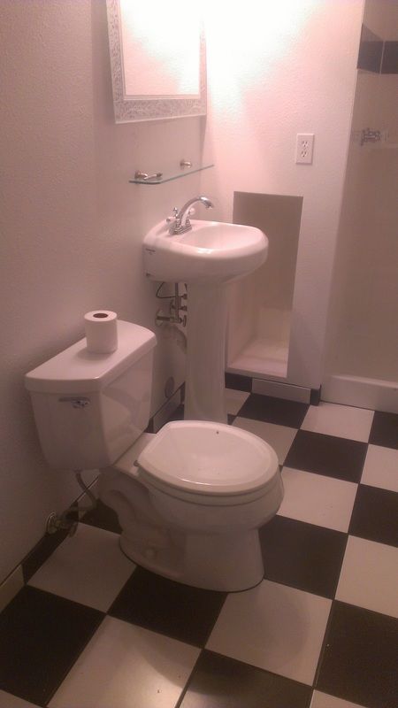 A bathroom with a toilet , sink and checkered floor.