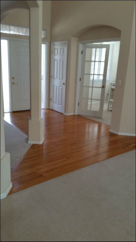 An empty living room with hardwood floors and white walls