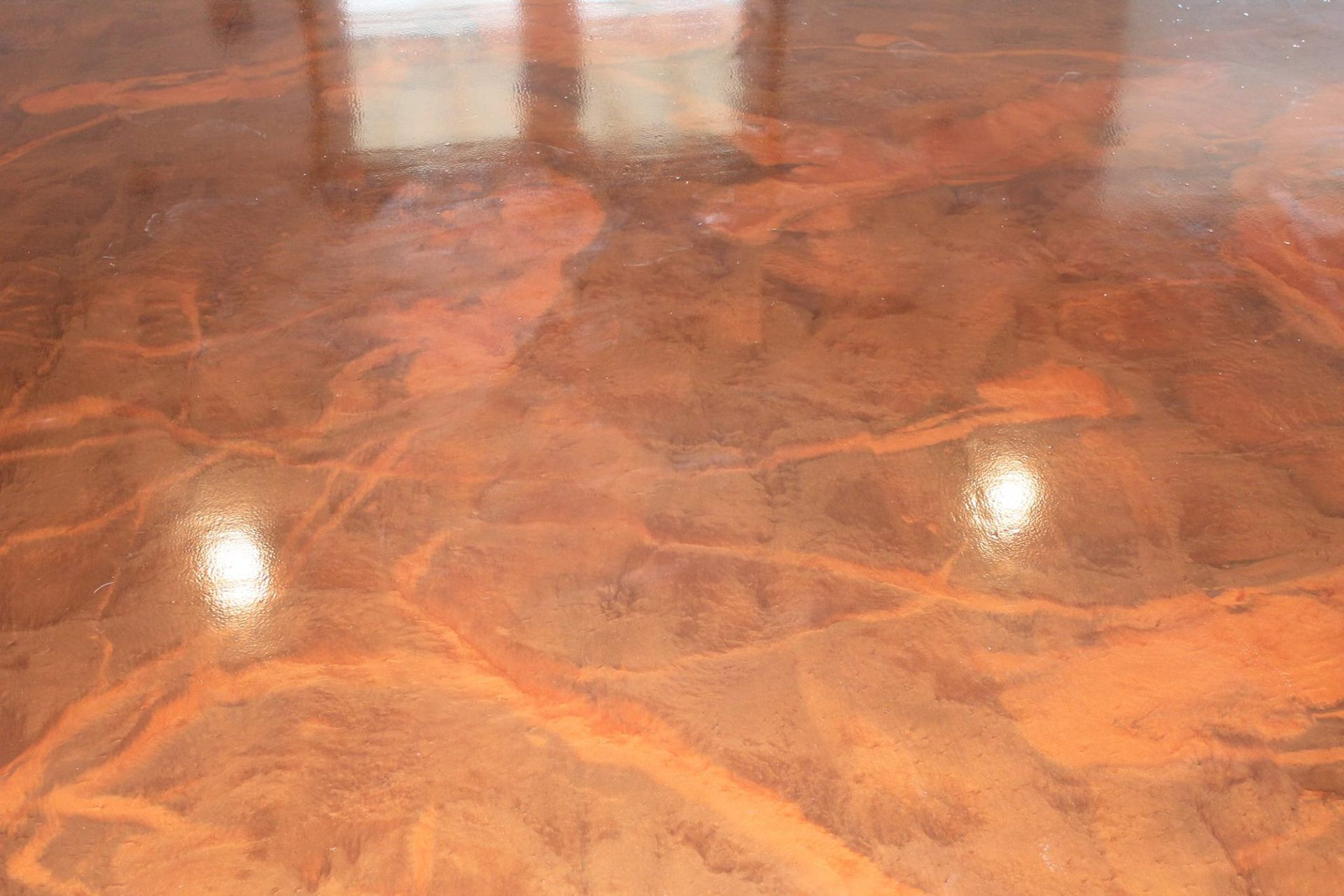 Glossy orange-brown marbled floor with reflections of overhead lights