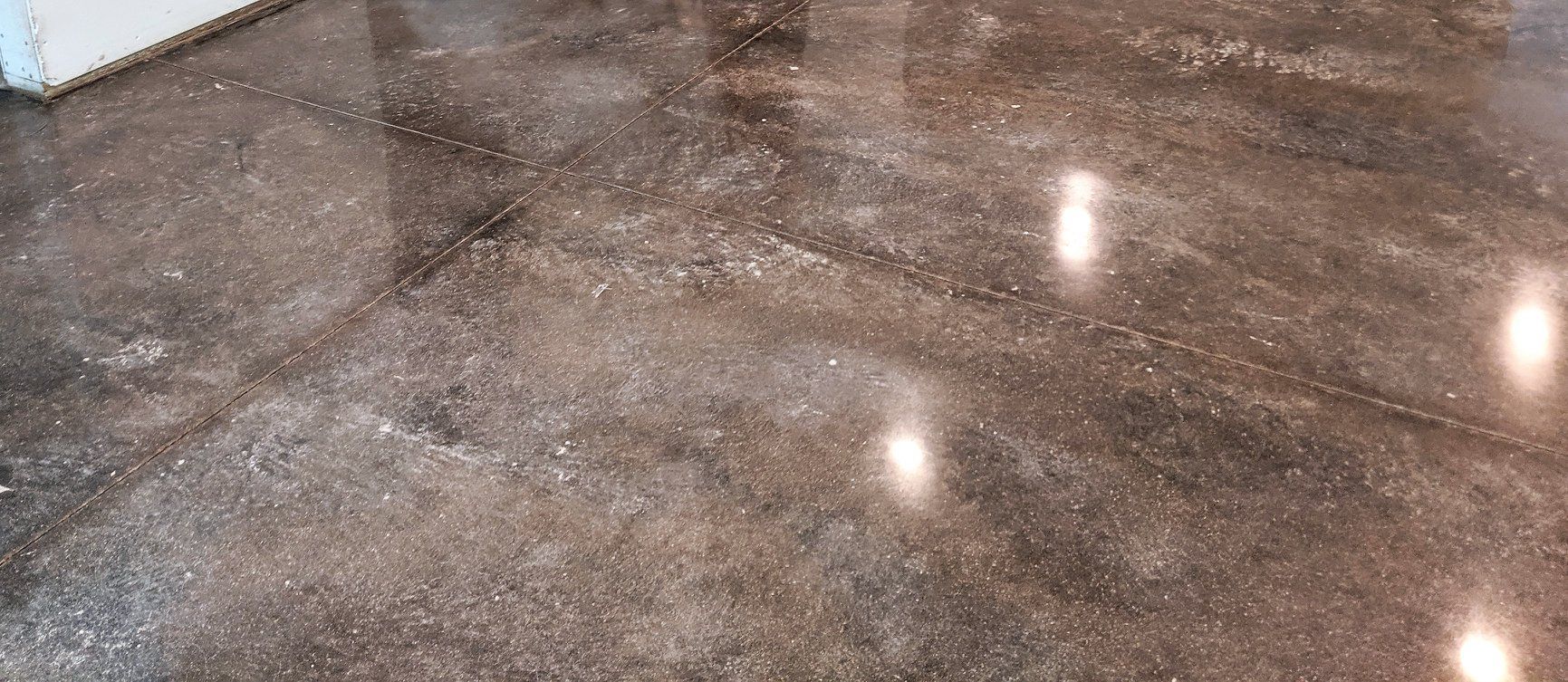 Shiny brown speckled polished stone floor with reflections of overhead lights