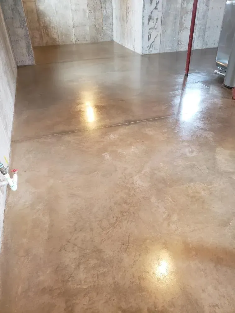 Polished concrete floor in an empty room with light reflections and tiled walls