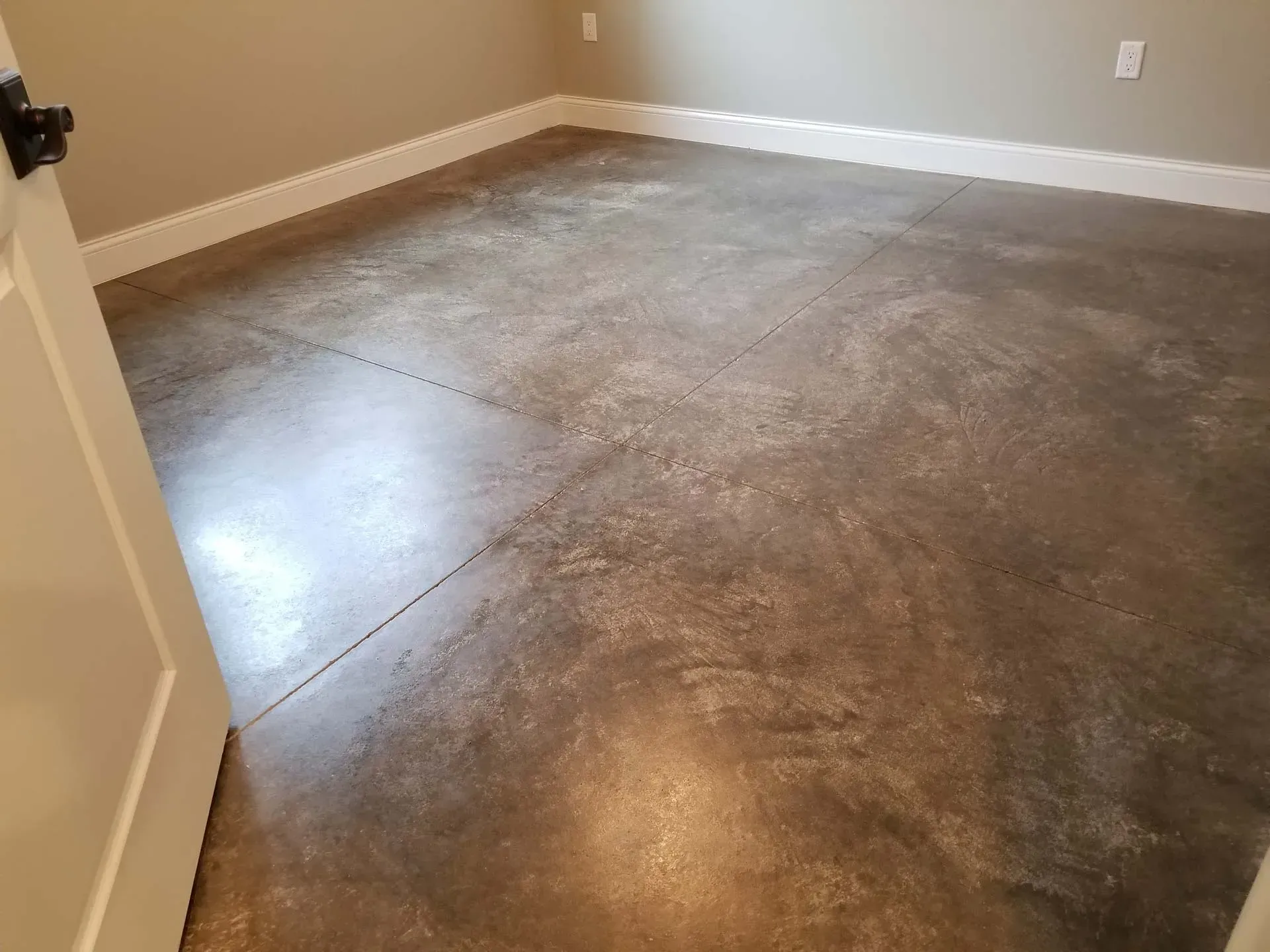 Empty room with polished concrete floor and beige walls, viewed through an open door.