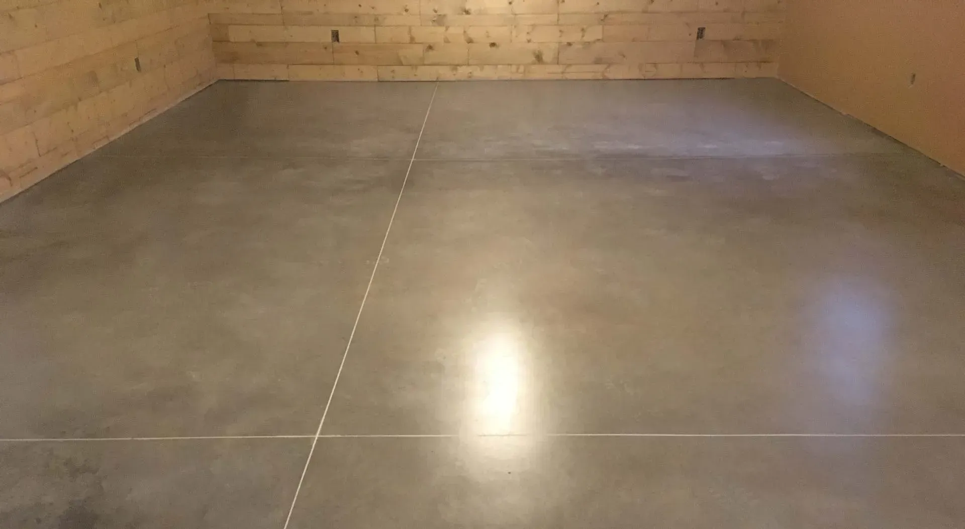 Empty concrete basement with gray floor and wood-paneled walls