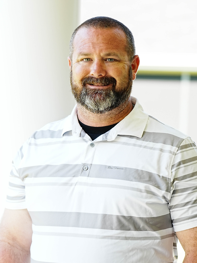 A man in a blue suit and white shirt is smiling for the camera.
