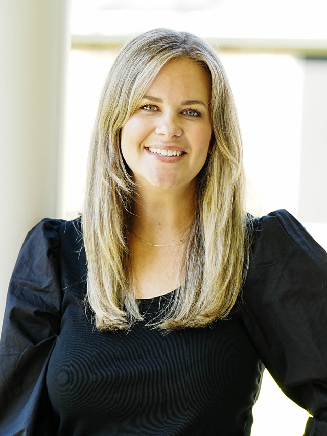 The woman is wearing a black sweater and smiling for the camera.
