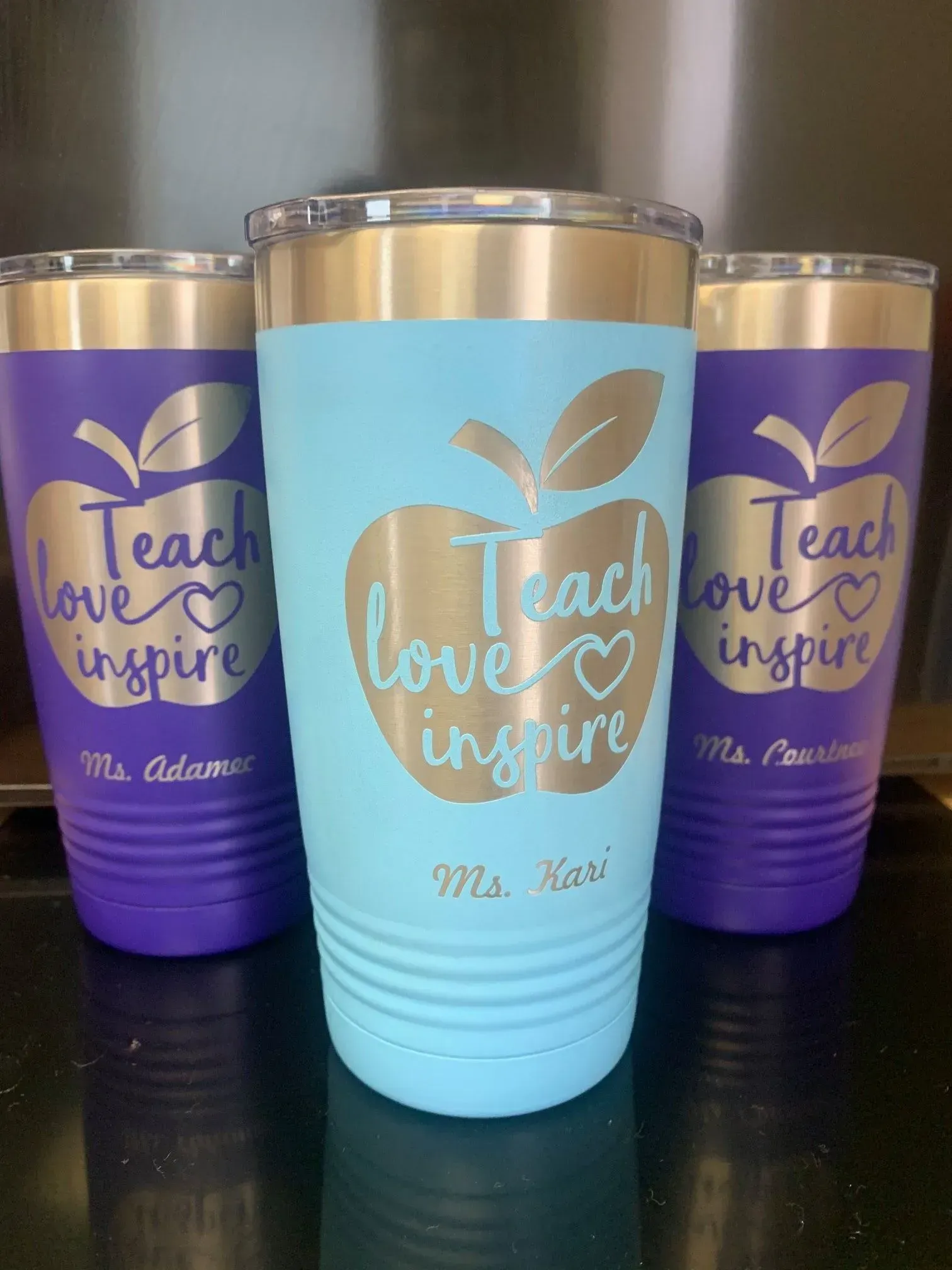Three tumblers with apples on them that say teach love inspire