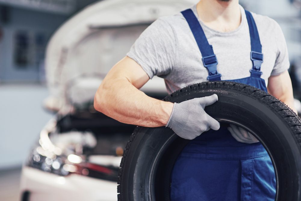Mechanic With Gloves Carrying Tire — Brake Specialists in Molendinar, QLD