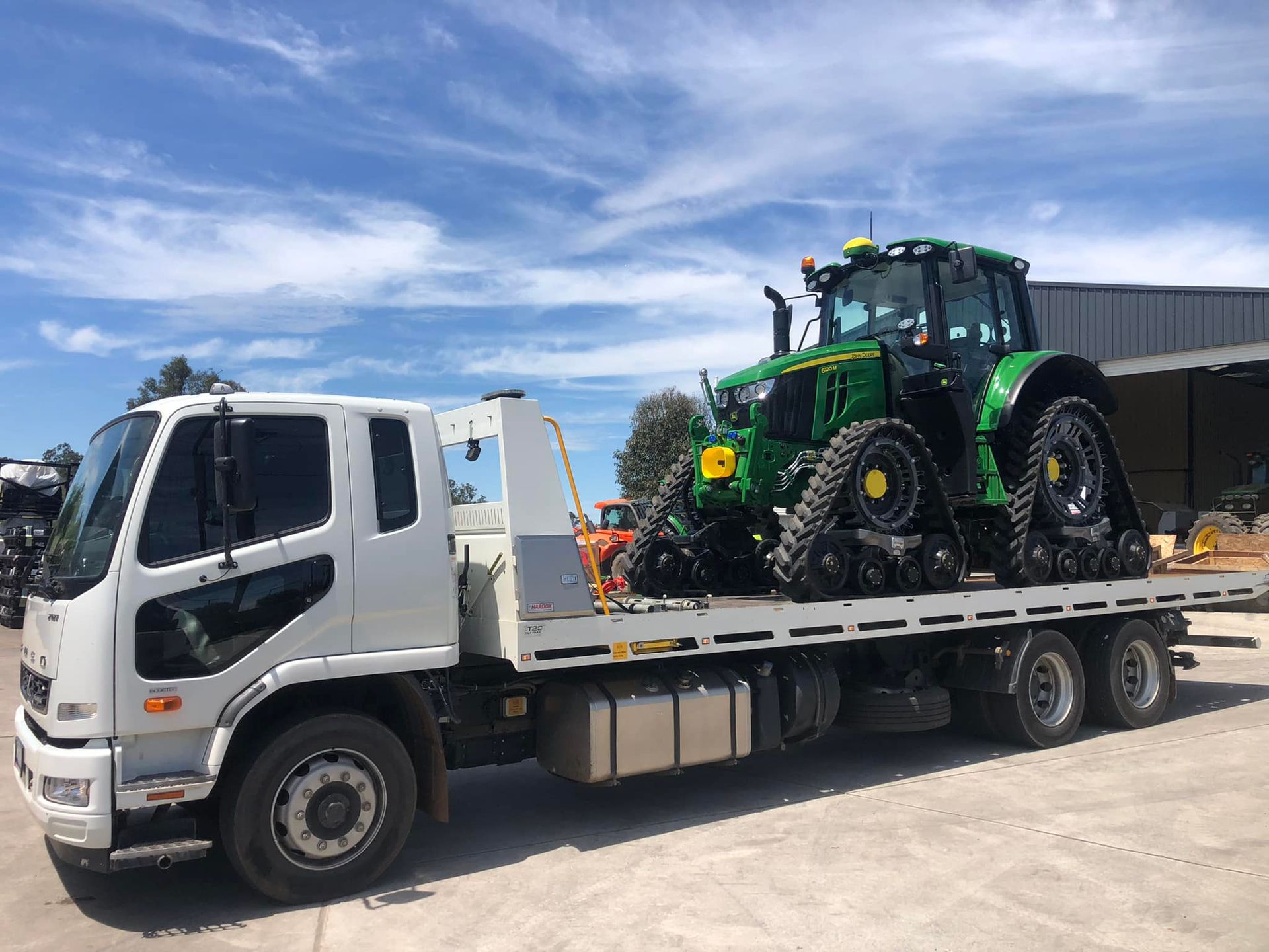 White Flatbed Truck Transporting a Green Tractor — ASAP Towing Pty Ltd In Tiaro, QLD