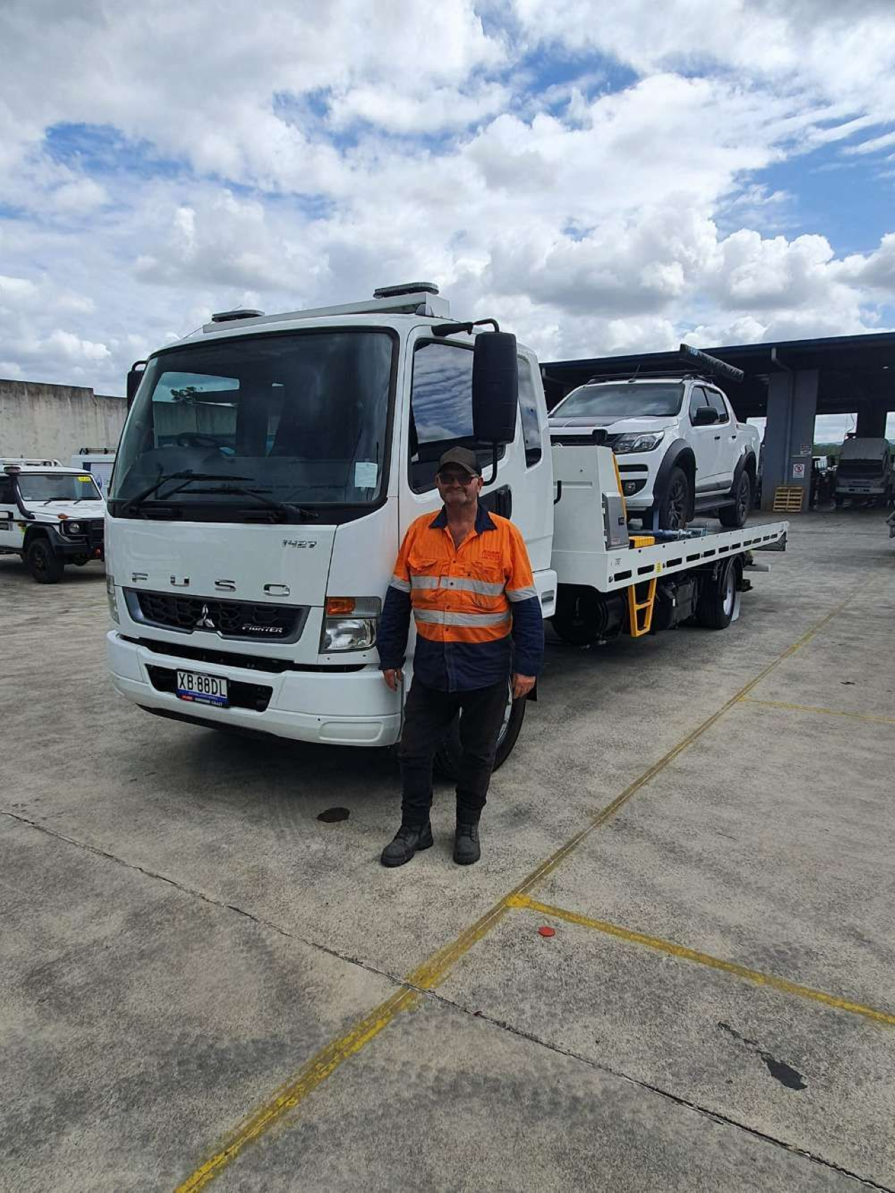 Man Standing in Front of a White Tow Truck With a Car on the Back — ASAP Towing Pty Ltd In Gympie, QLD