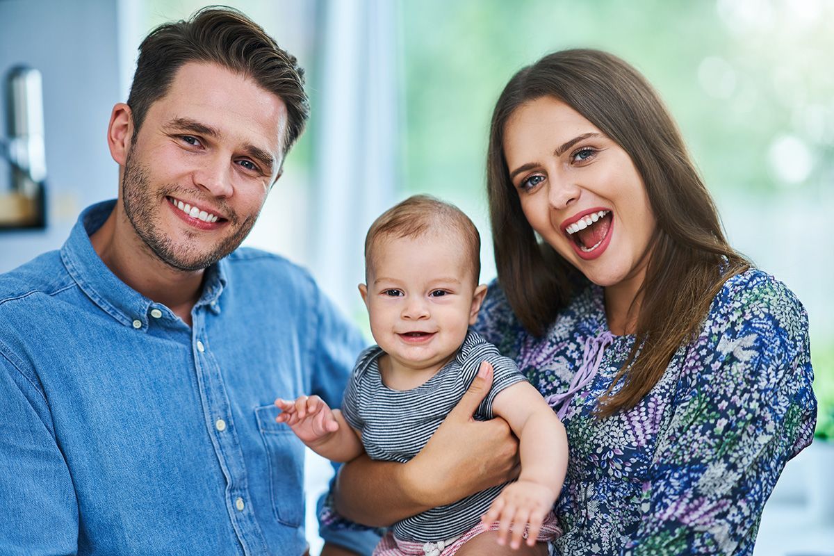 Happy family with a baby, indoors. Smiling parents hold the smiling infant.