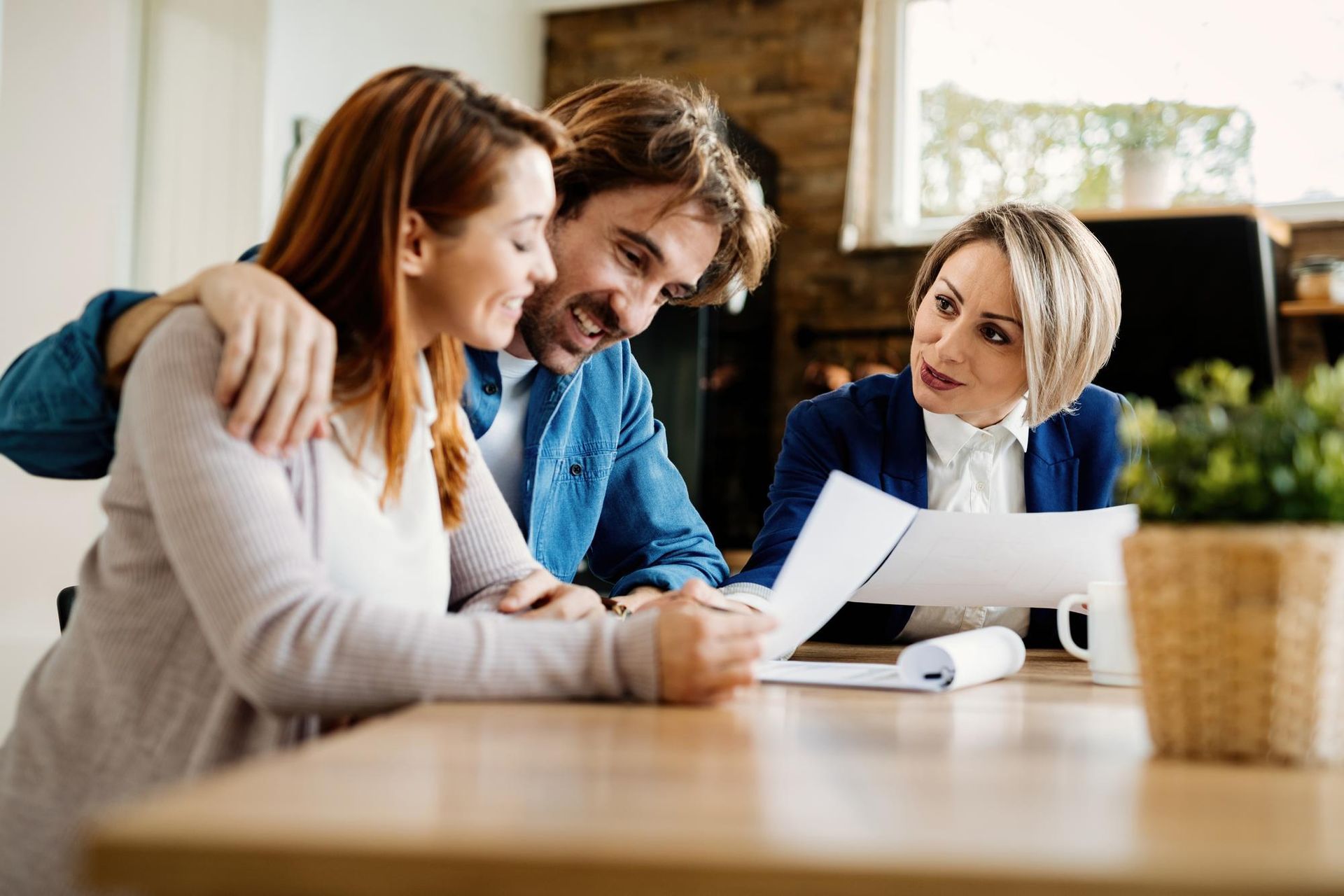 Three coworkers reviewing documents together at a wooden table in a bright office