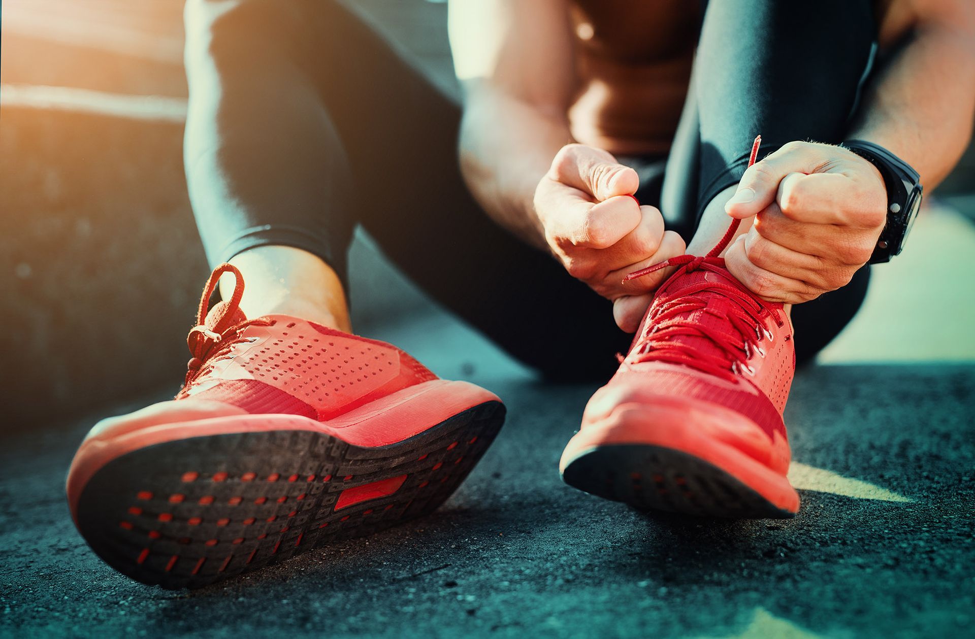 Person tying red running shoe laces before a workout.