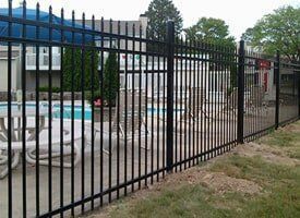 A black metal fence surrounds a swimming pool.