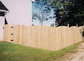A wooden fence is sitting in the grass in front of a house.