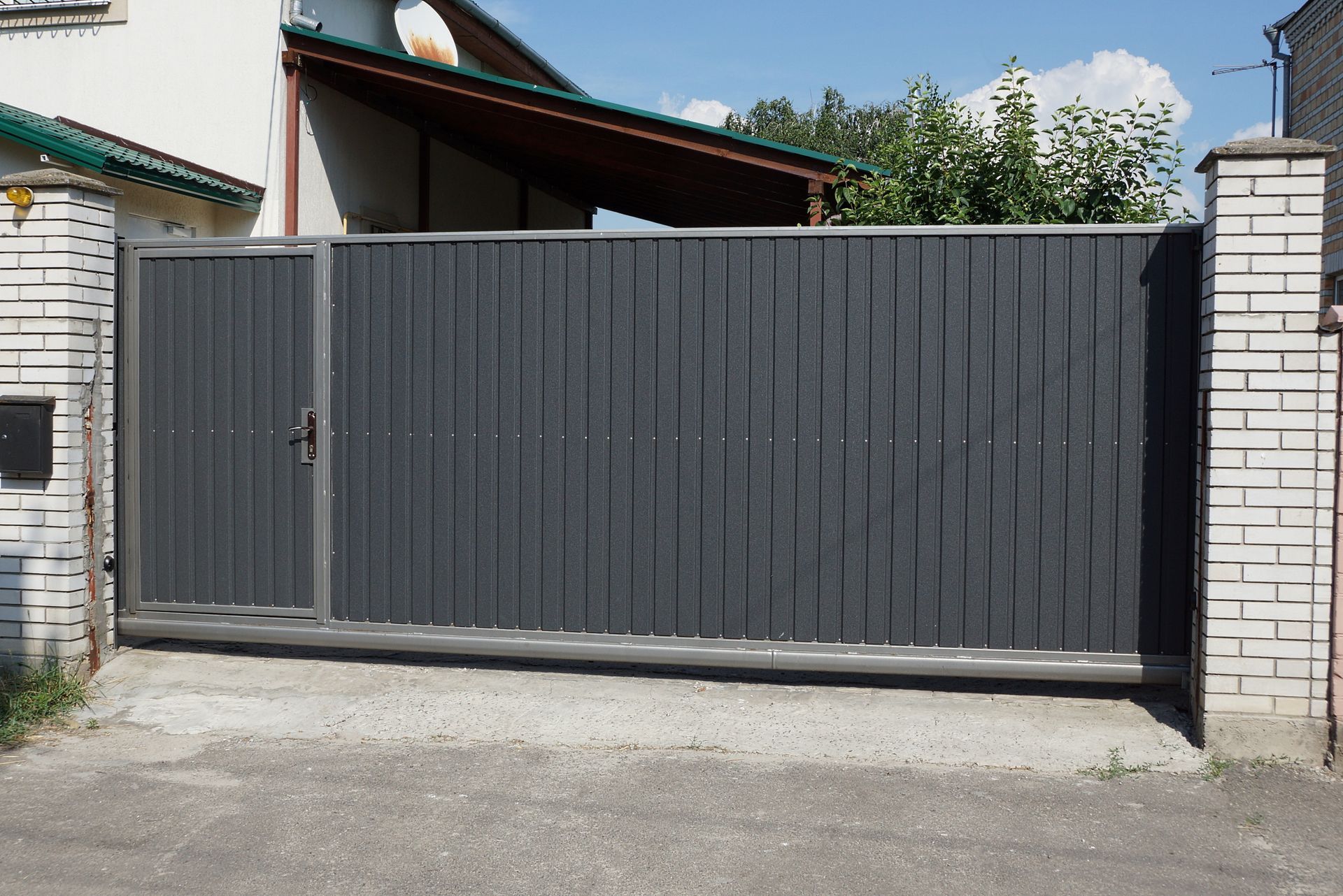 A black sliding gate is open in front of a house