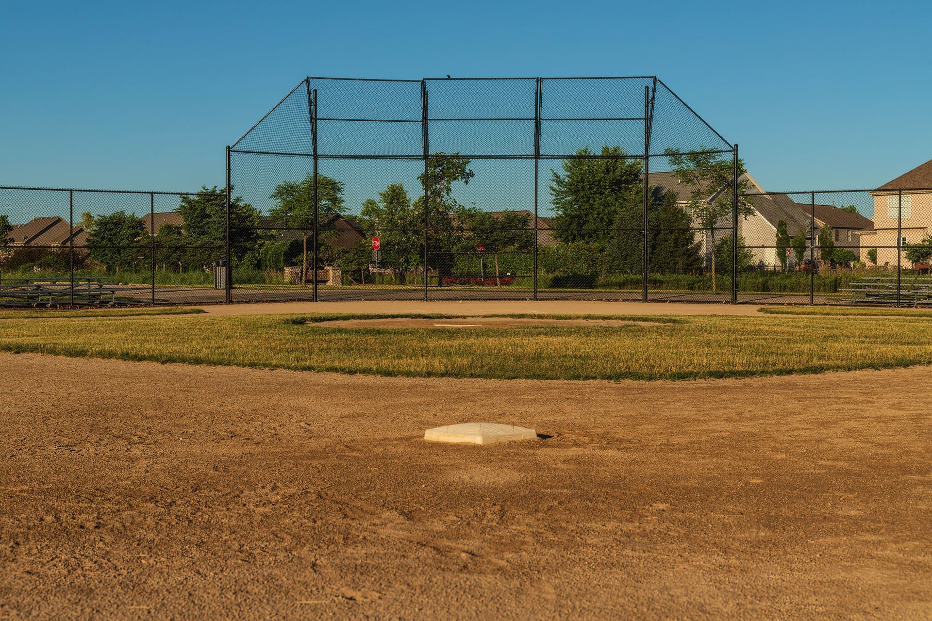 An empty baseball field with a fence and a base