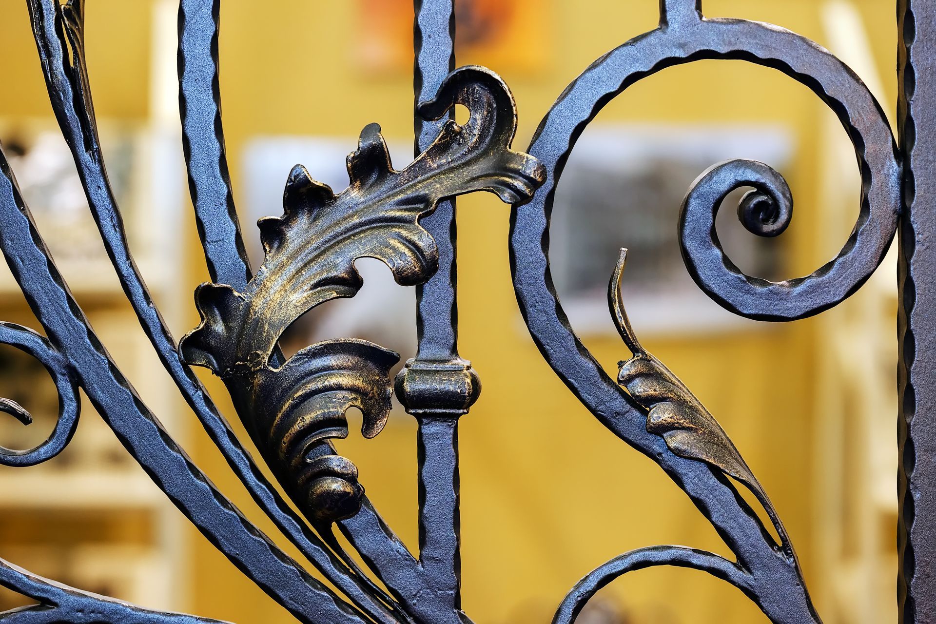A close up of a wrought iron fence with a leaf design