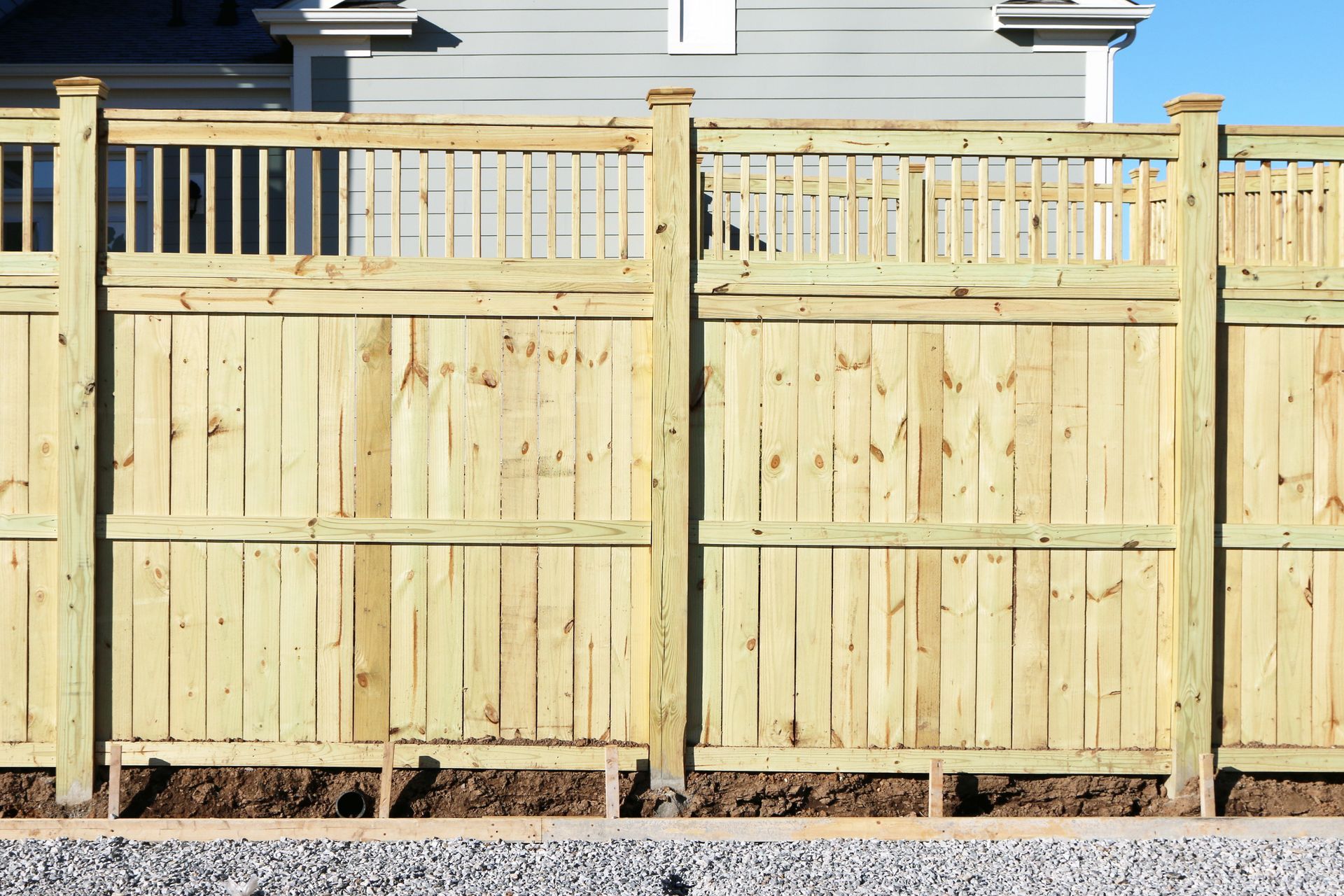 A wooden fence is sitting in front of a house.