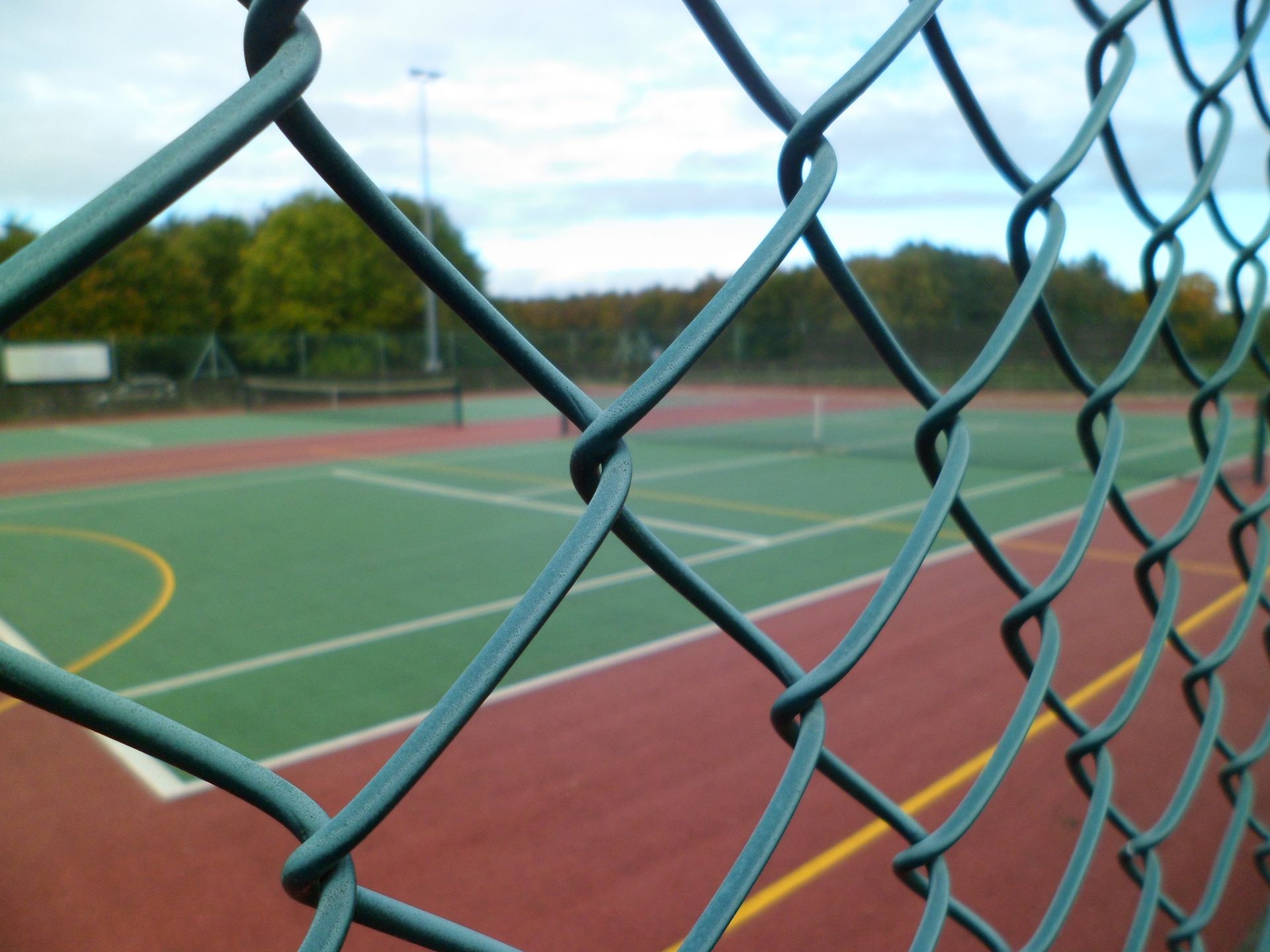 A tennis court is behind a chain link fence