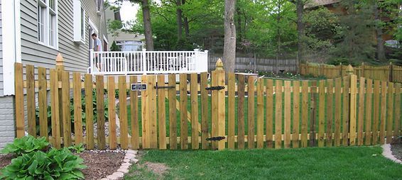 A wooden picket fence is in the backyard of a house.