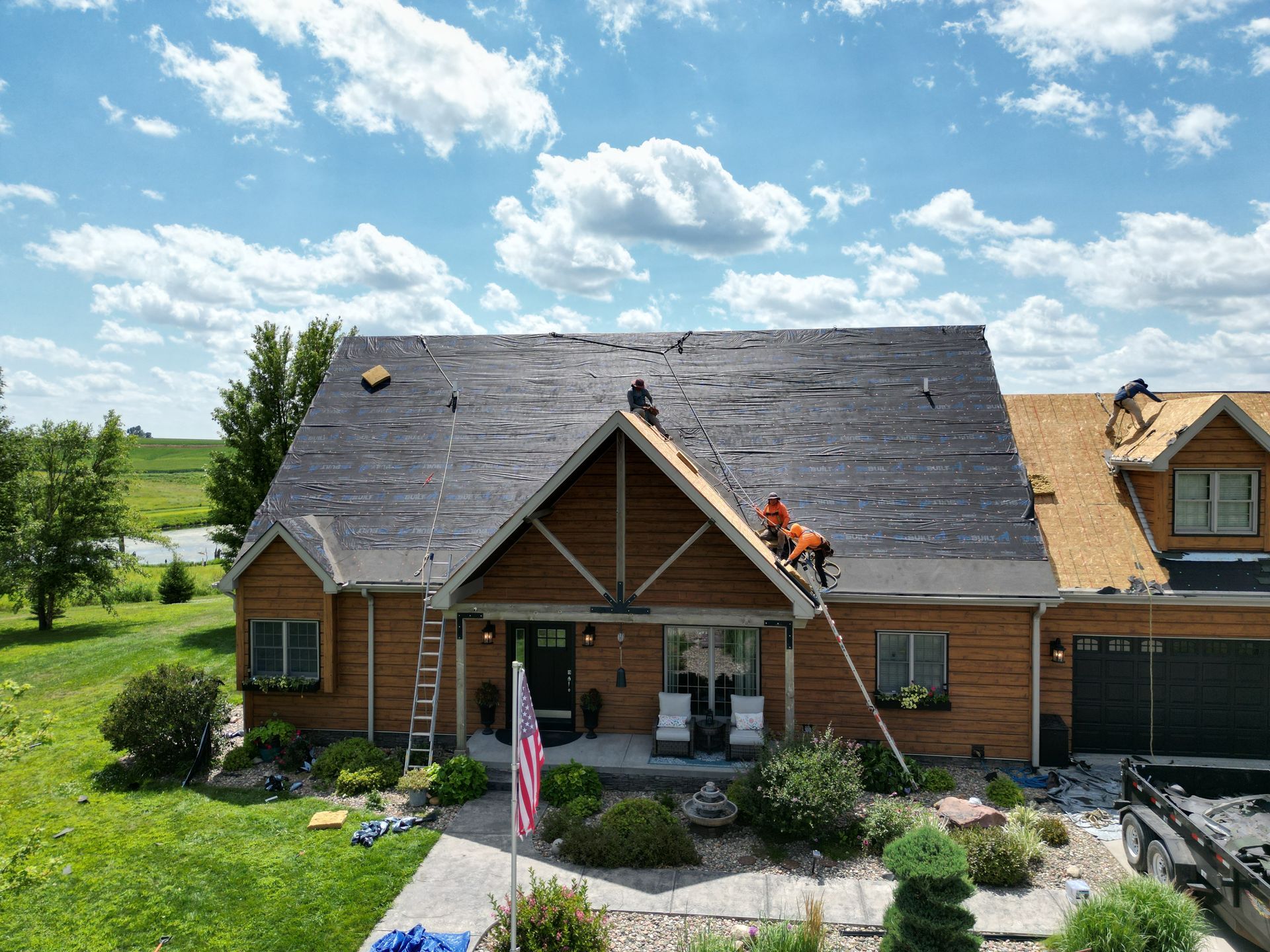 Two construction workers are working on the roof of a building.