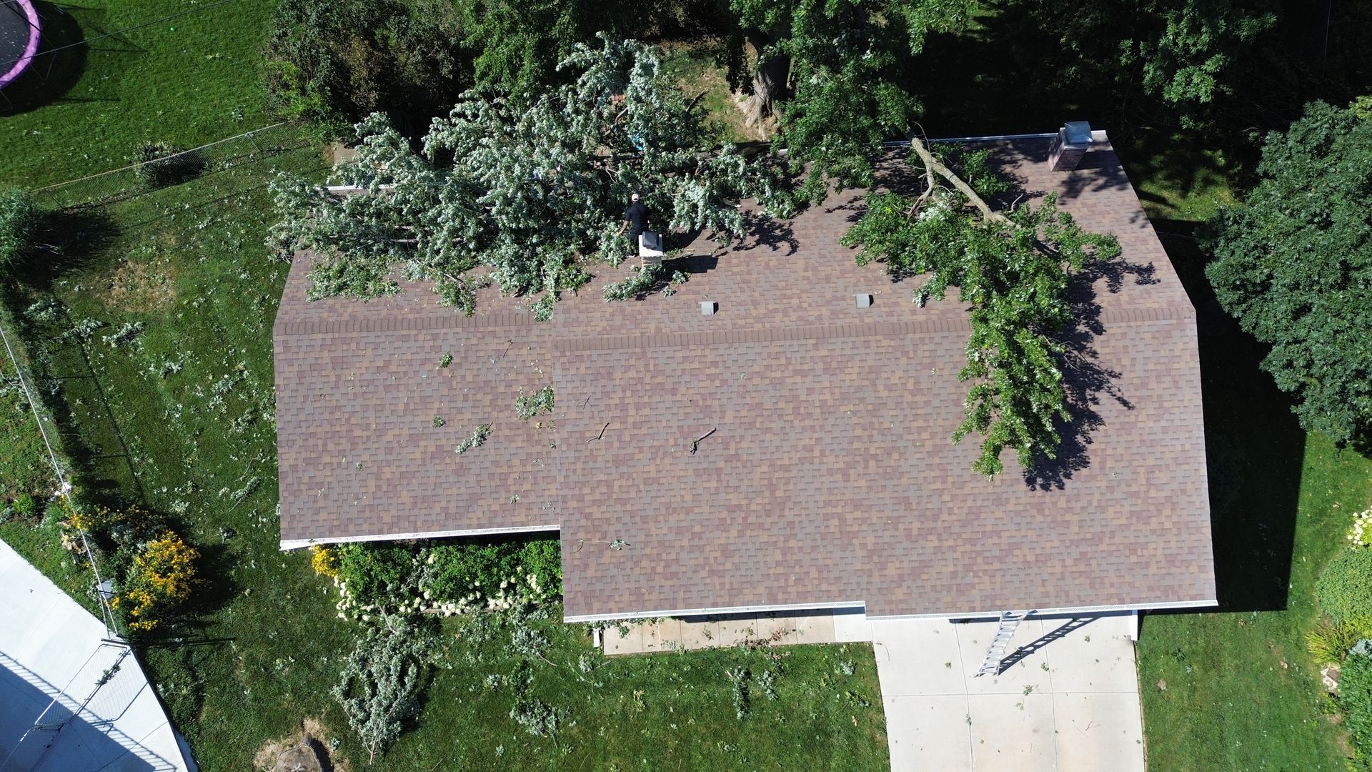 A man wearing a hard hat and safety vest is working on a roof.