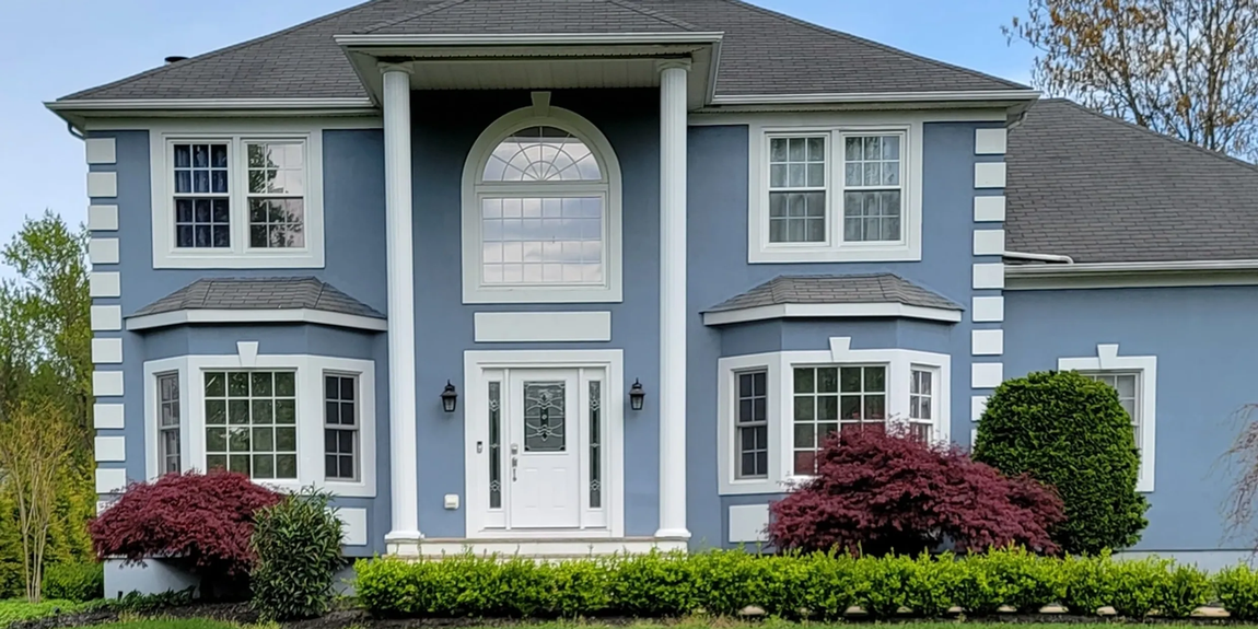 A large blue house with white trim and columns