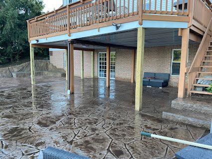 Flooded backyard beneath a raised deck and stairs, with muddy water covering the ground.