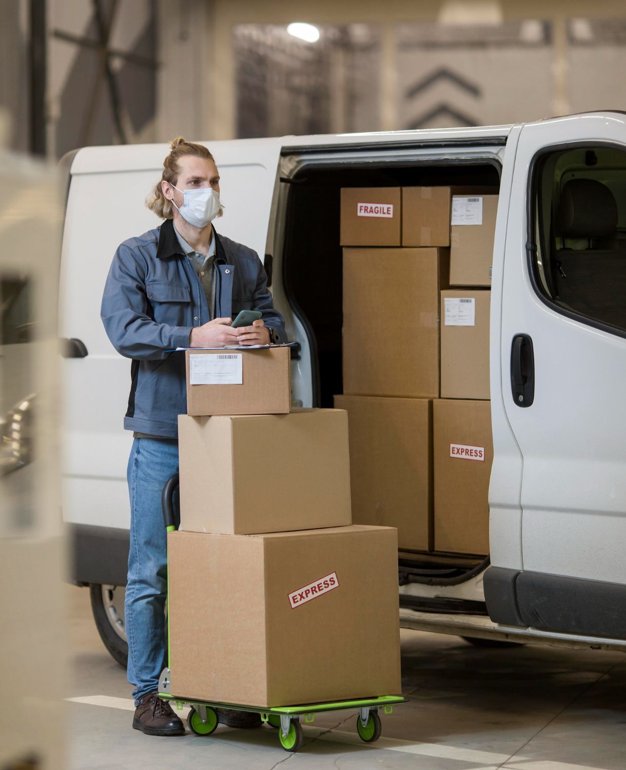A man wearing a mask is loading boxes into a van.