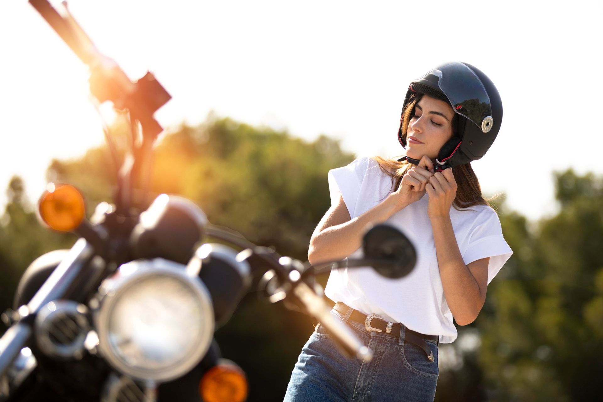 A woman wearing a helmet is standing next to a motorcycle.