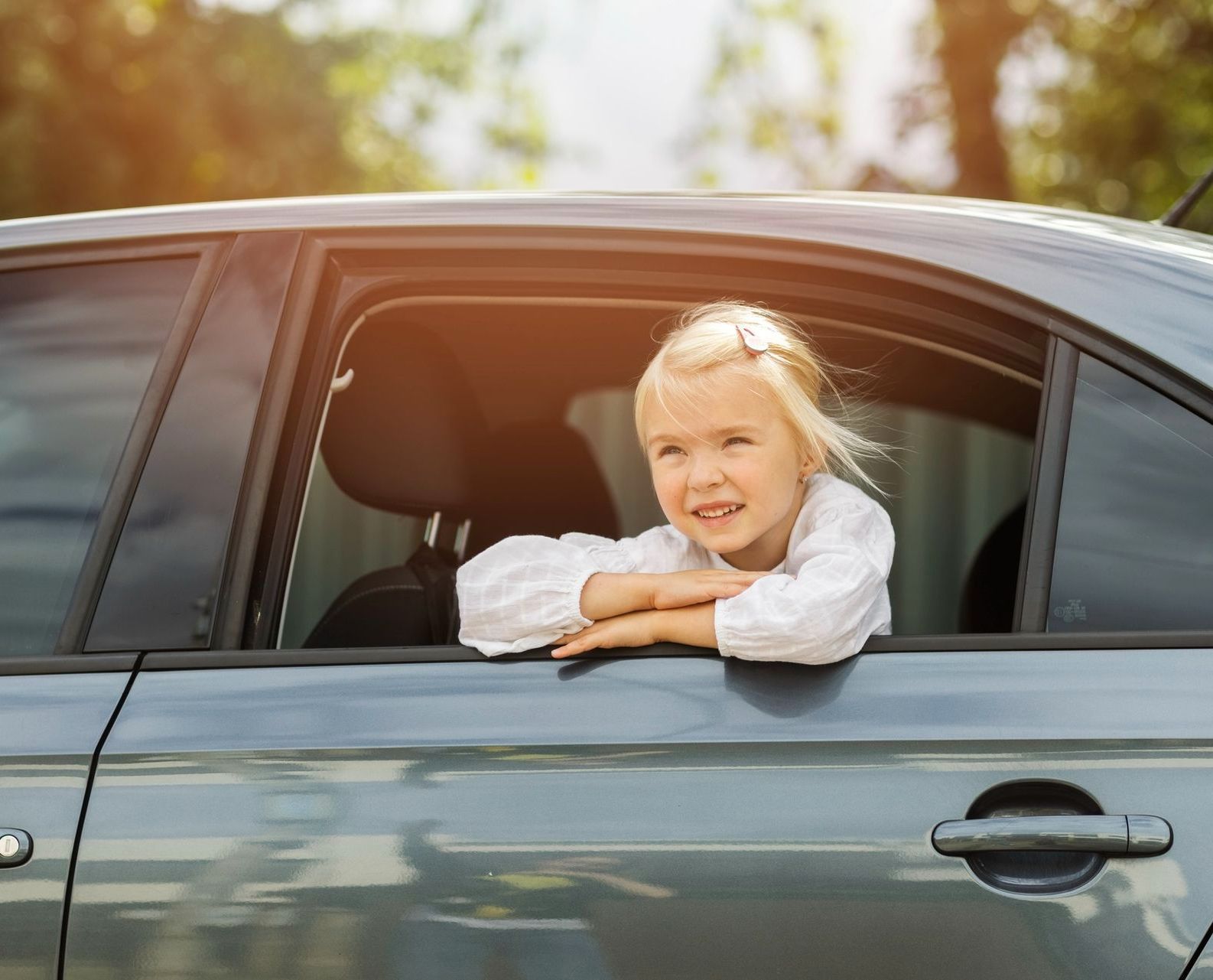 A little girl is looking out of the window of a car.